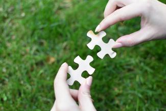 Hands holding 2 pieces of the puzzle